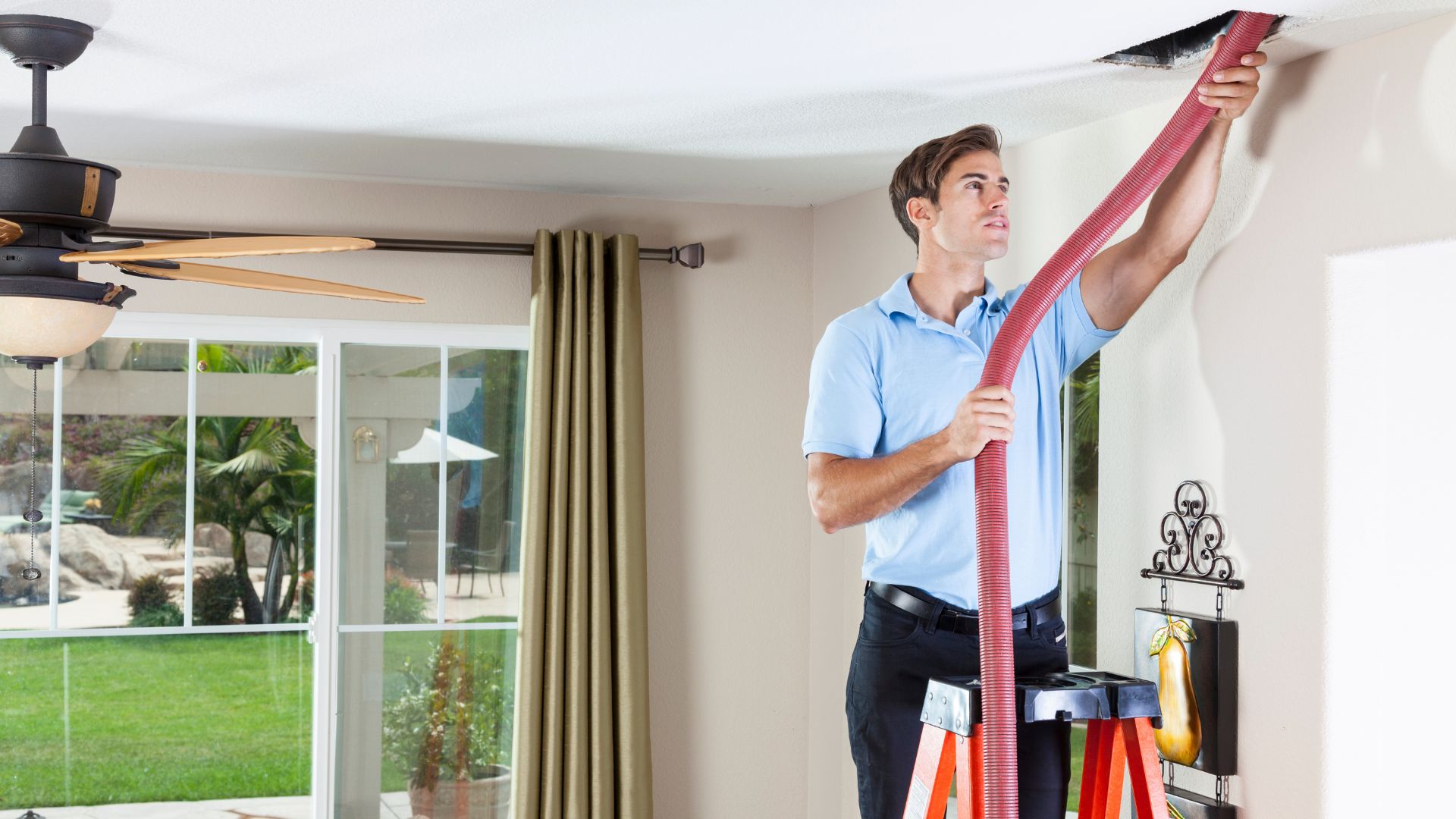 Technician using red vacuum hose to clean air vent in home interior