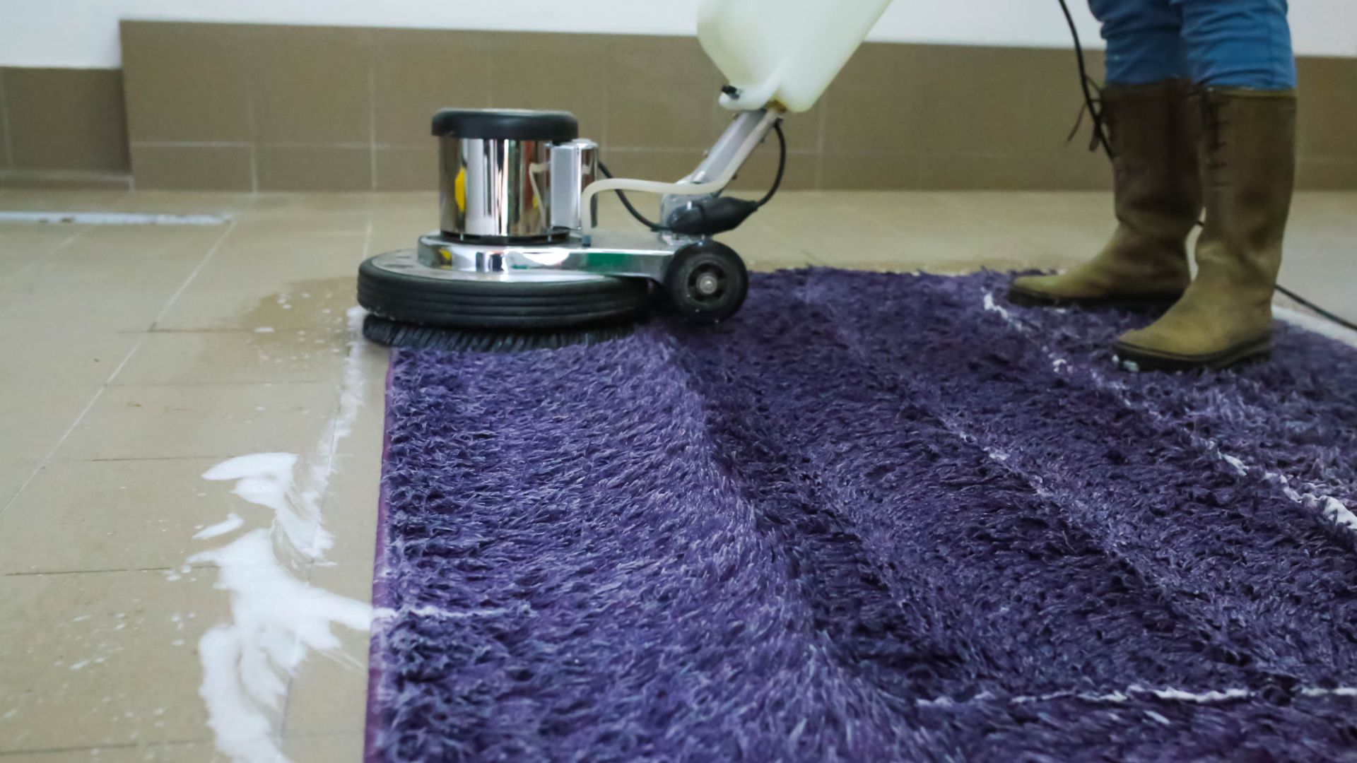 Professional carpet cleaning machine on purple rug with cleaning solution
