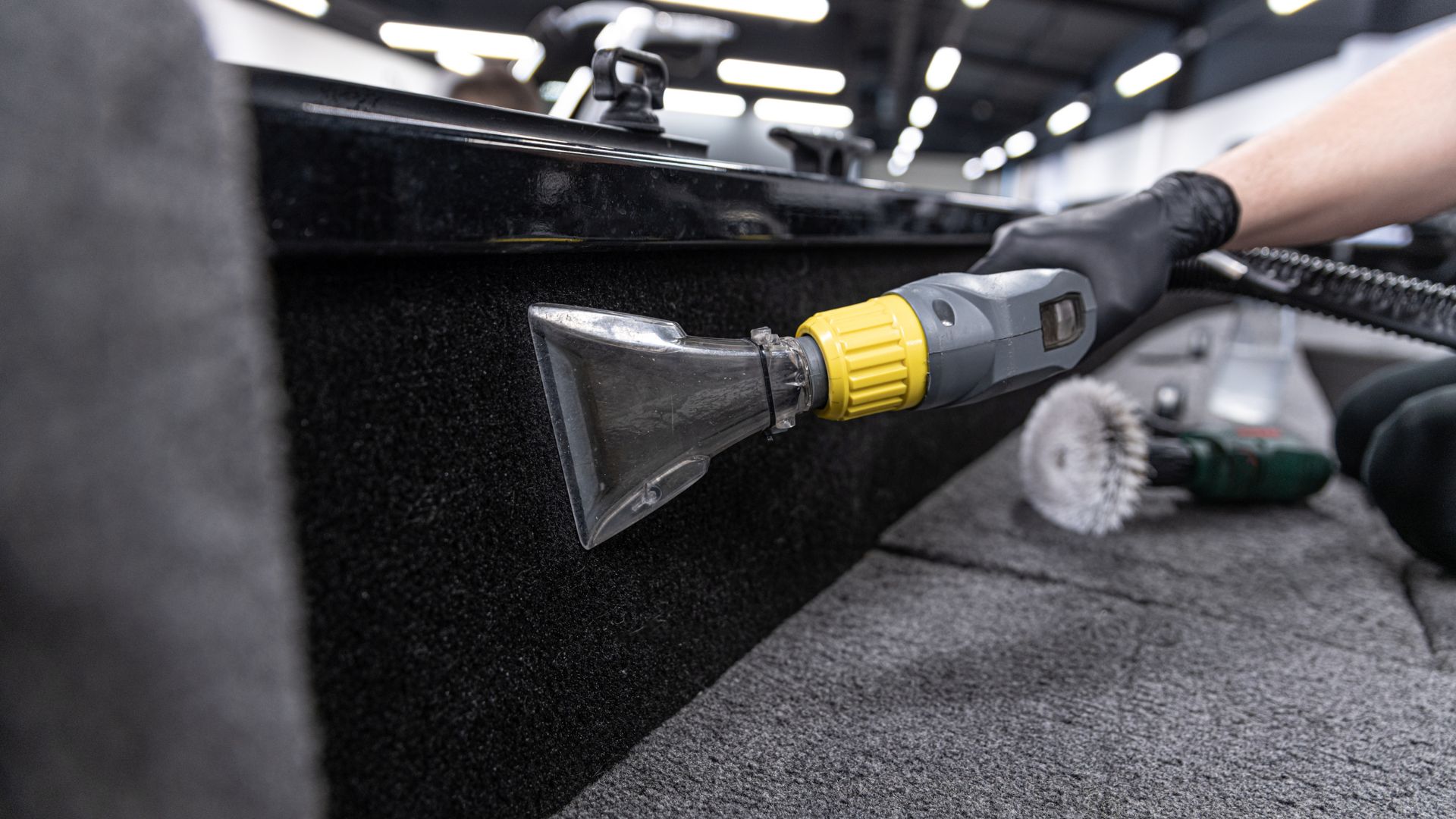 Professional cleaning tool extracting dirt from car interior carpet