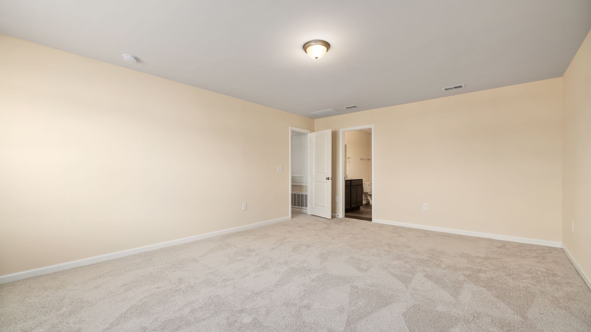 Empty room with beige walls, carpet, and white doors
