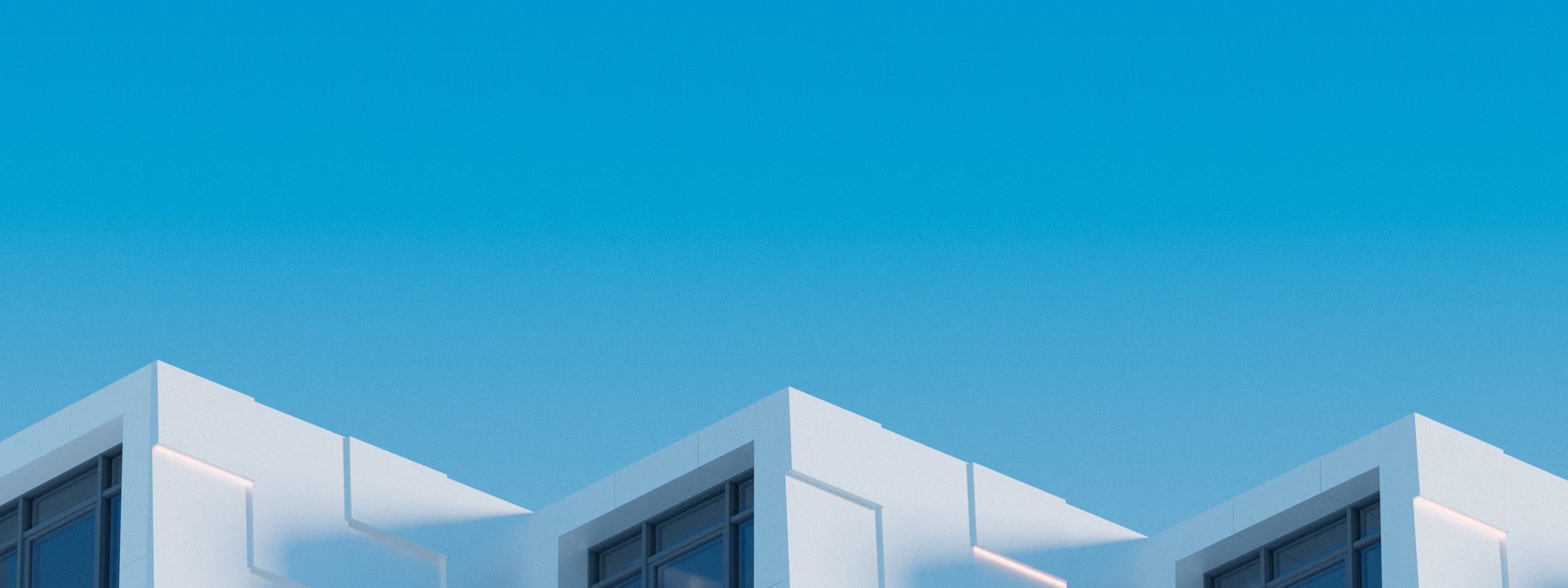 Modern white buildings with large windows against clear blue sky