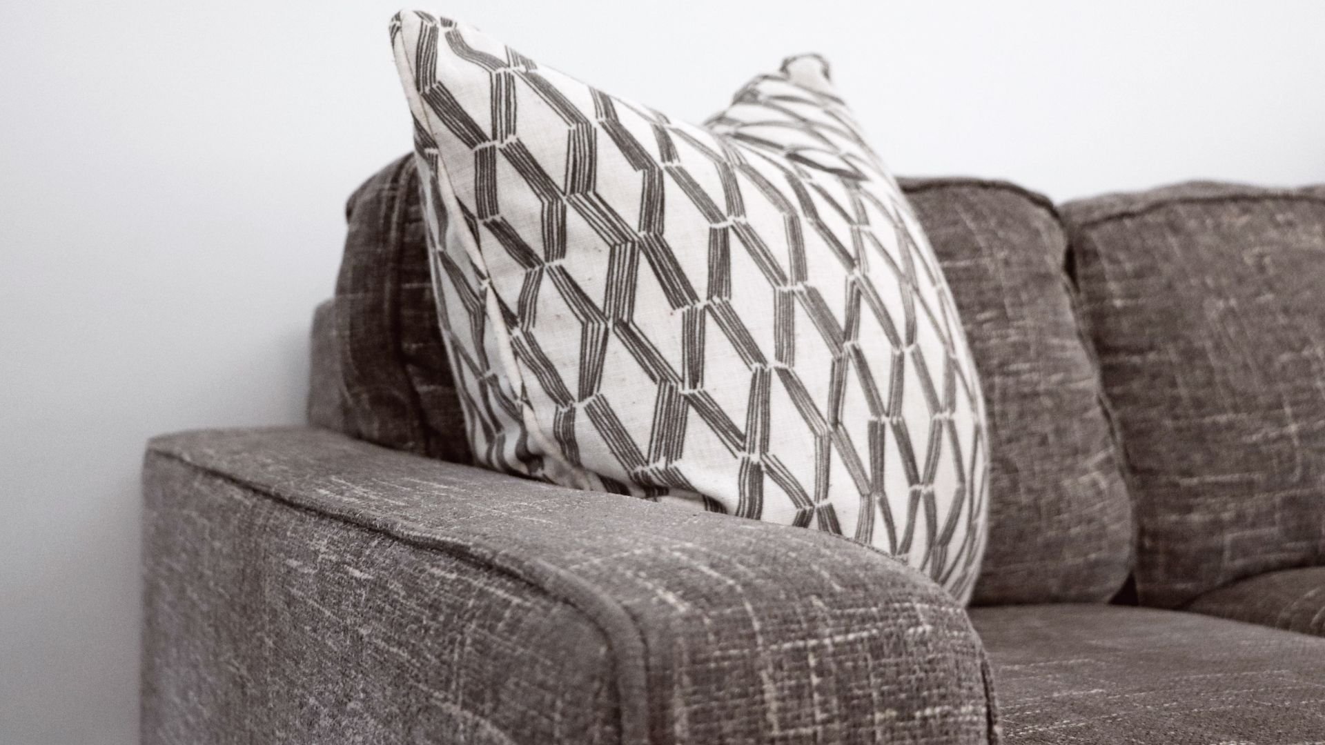 Gray textured sofa with decorative white and gray geometric patterned pillows
