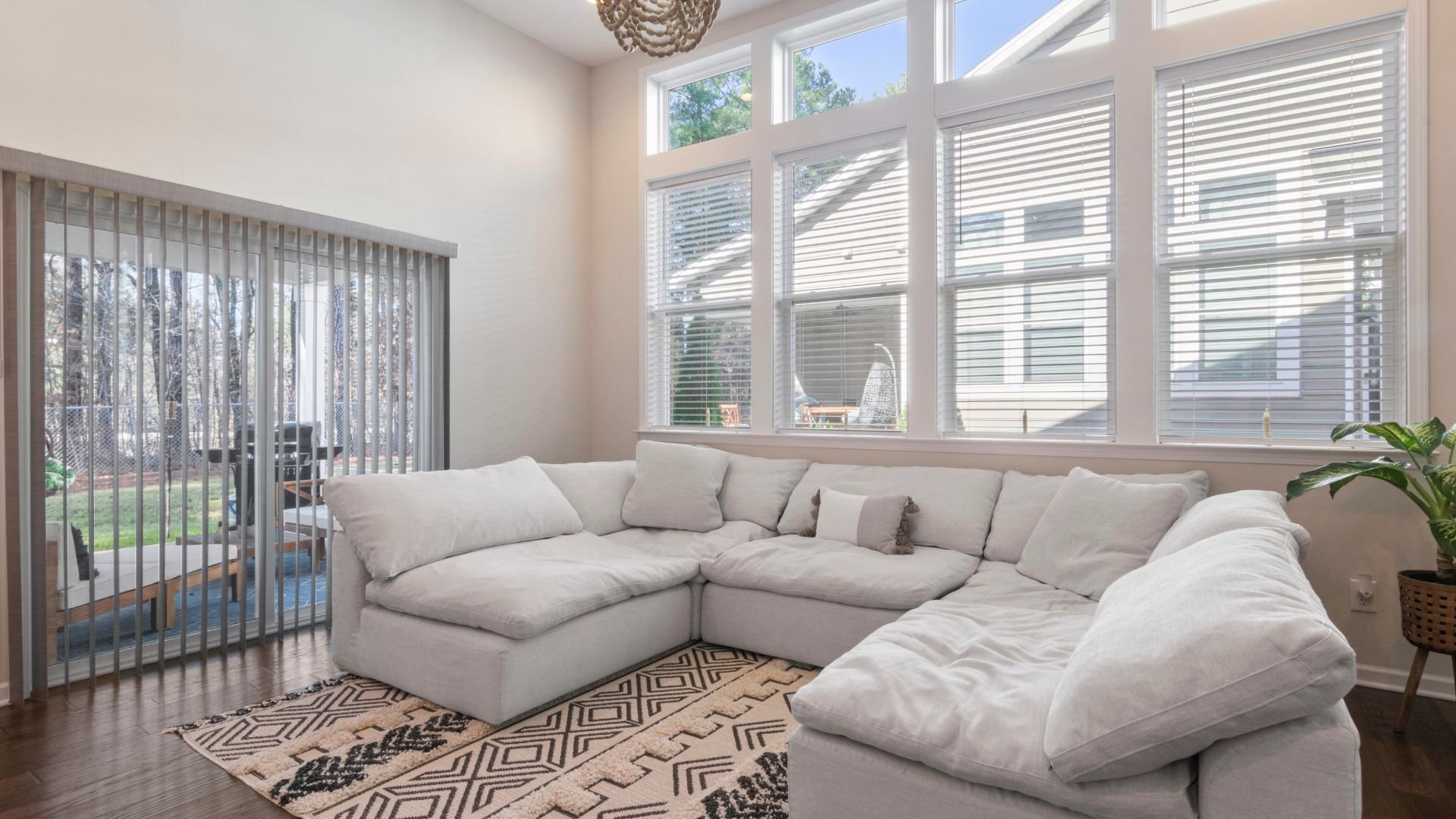 Bright living room with large windows, white sectional sofa, and patterned rug
