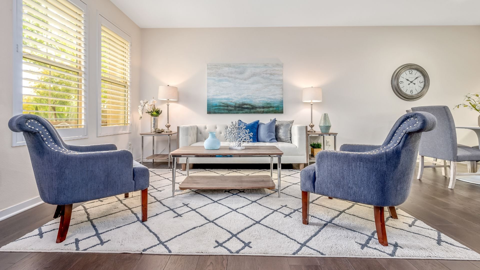 Modern living room with blue chairs, white sofa, and coastal artwork